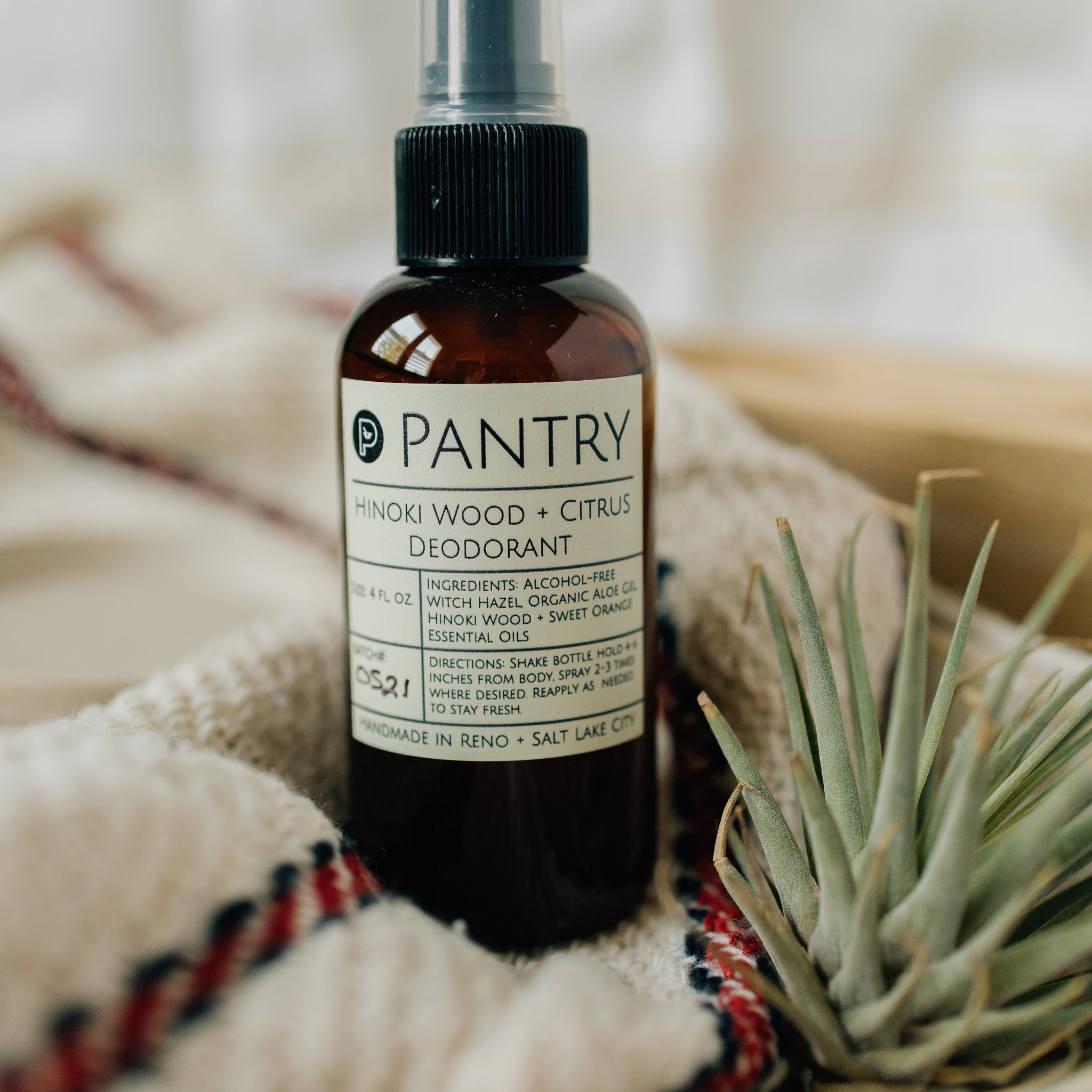 Pantry deodorant bottle on a textured surface with a plant in the background