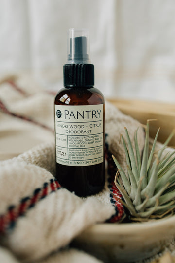 Pantry deodorant bottle on a textured surface with a plant in the background