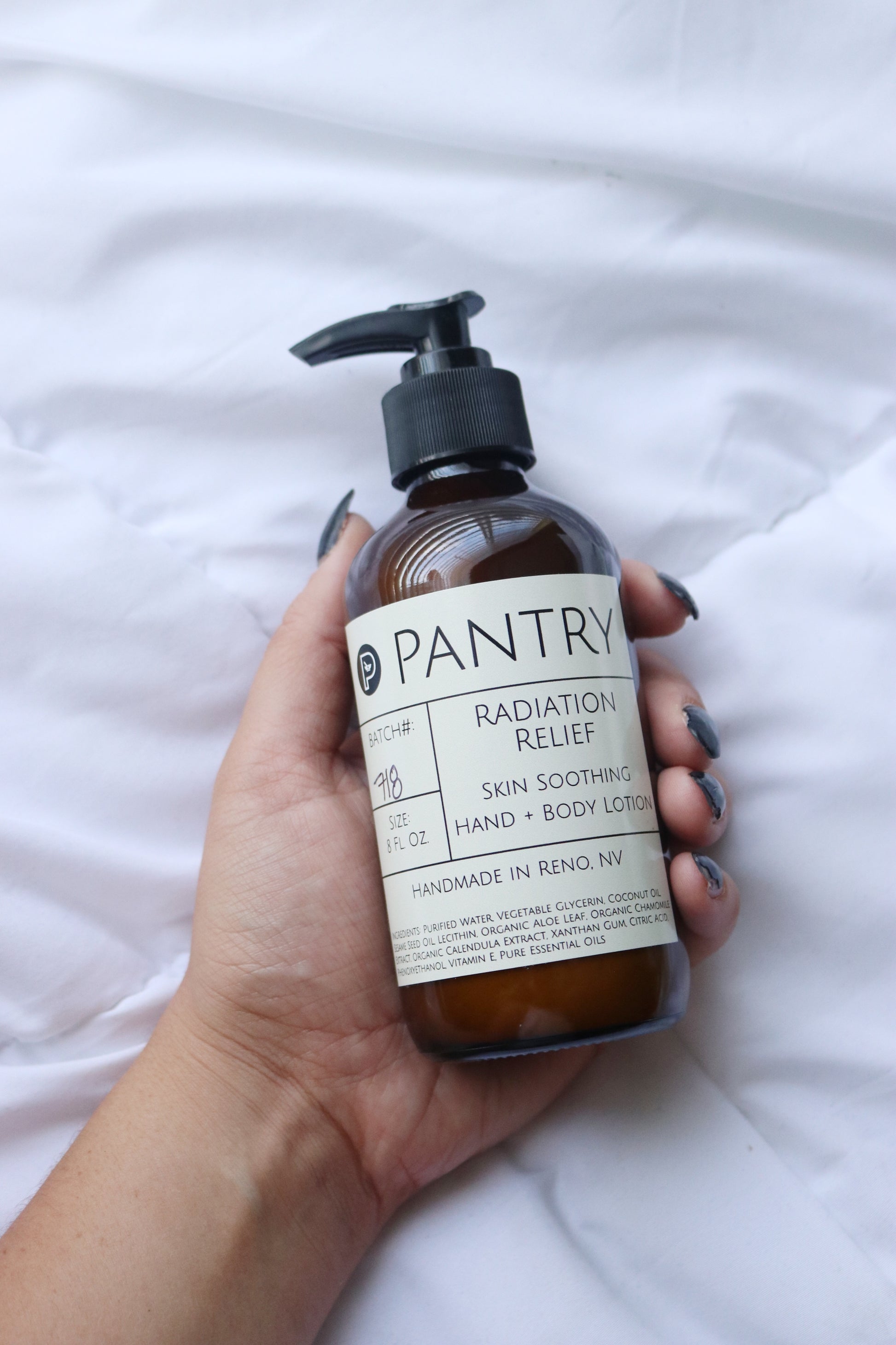 Hand holding a bottle of Pantry lotion on a white background